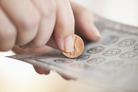 Studio shot of woman scratching lottery ticket.