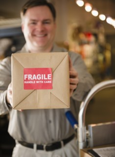 Delivery man holding box with fragile sign. Photo : Jamie Grill Photography
