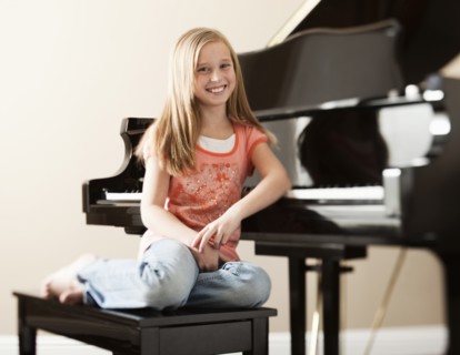 Portrait of girl (8-9) sitting by piano. Photo : Mike Kemp