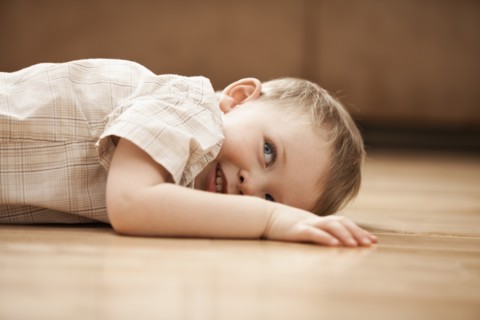 Portrait of smiling boy (2-3) lying on floor. Photo: Mike Kemp