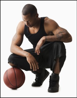 Studio shot of man with basketball crouching. Photo : Mike Kemp