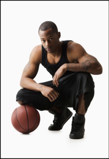 Studio shot of man with basketball crouching. Photo : Mike Kemp