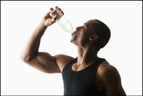 Studio shot of man drinking water from bottle. Photo : Mike Kemp