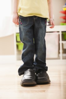 Girl (2-3) standing in dad's shoes, low section. Photo: Mike Kemp