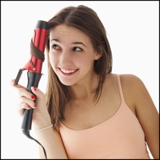 Young woman curling hair. Photo: Mike Kemp