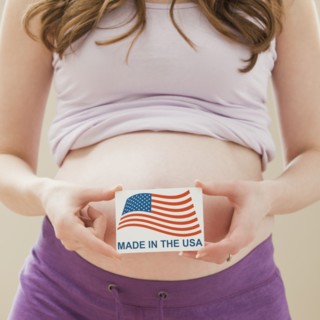 Young pregnant woman holding Made in the USA Sign. Photo: Mike Kemp