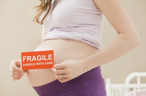 Young pregnant woman holding fragile sign. Photo : Mike Kemp