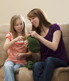 Mother giving daughter (8-9) knitting tips. Photo : Mike Kemp