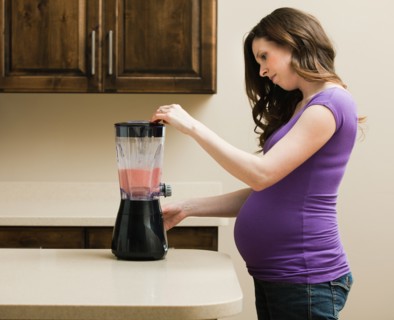 Young pregnant woman using juice extractor. Photo : Mike Kemp