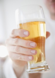 Hand holding glass of beer. Photo : Jamie Grill Photography