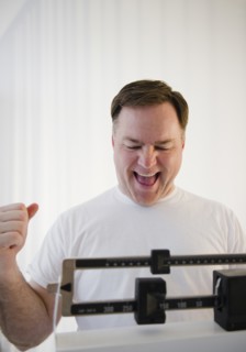Man on weight scales laughing. Photo : Jamie Grill Photography