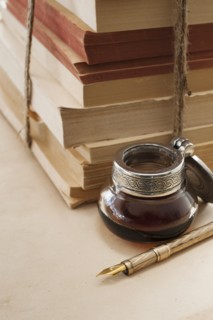 Close up antique ink well, pen and books.