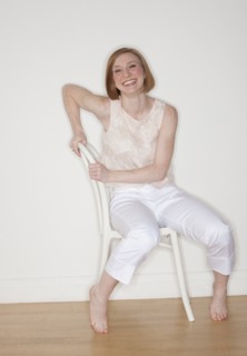 Studio shot of woman sitting on chair and smiling.