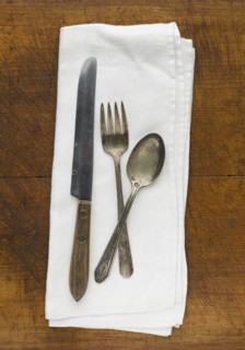 Close up of silver forks, knife and spoon on napkin.