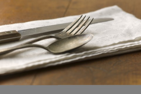 Close up of silver forks, knife and spoon on napkin.