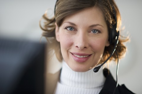 Portrait of smiling woman with headset in customer service office.