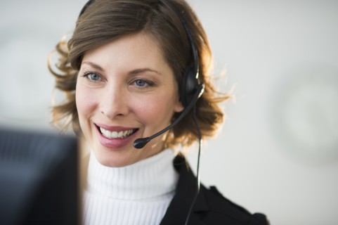 Portrait of smiling woman with headset in customer service office.