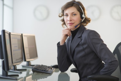 Portrait of smiling woman with headset in customer service office.