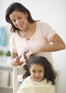 Mother cutting daughter's (6-7) hair.