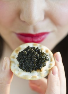 Young woman eating caviar snack, close-up of lips.