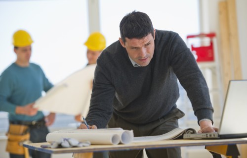 Architect preparing blueprintConstruction workers in background.