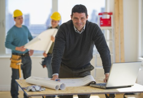Architect preparing blueprintConstruction workers in background.