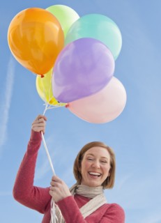 Woman holding bunch of balloons.