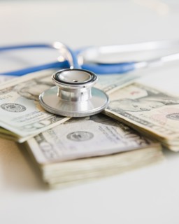 Studio shot of stethoscope on banknotes. Photo : Jamie Grill Photography