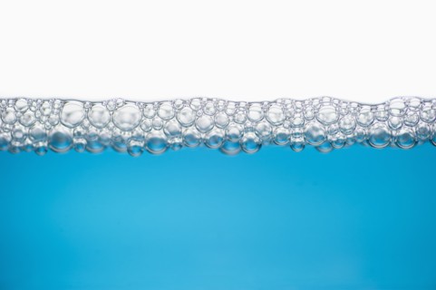 Close up of soap bubbles on water surface.