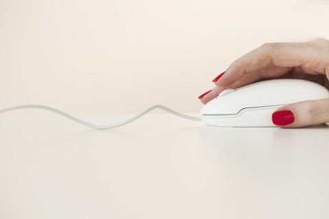Close up of woman's hand with red nail polish holding computer mouse.