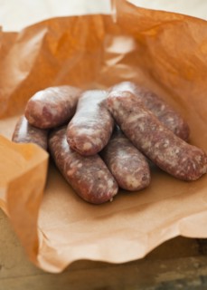 Studio shot of sausage wrapped in brown paper.