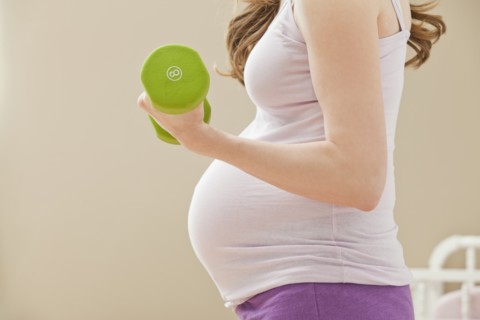 Young pregnant woman excercising with dumbbells. Photo: Mike Kemp