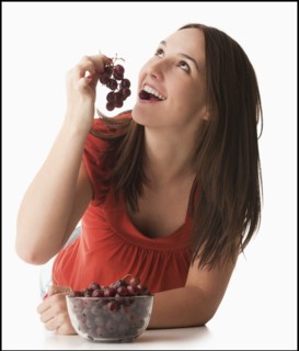 Young woman eating grapes. Photo : Mike Kemp