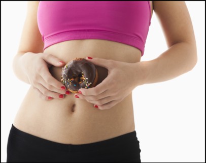 Young woman holding doughnut against belly. Photo: Mike Kemp