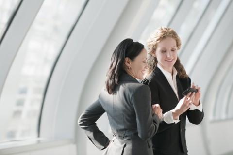 Businesswomen looking at cell phone. Photo: Mark Edward Atkinson