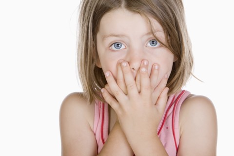 Studio portrait of girl (6-7) covering mouth. Photo : Justin Paget