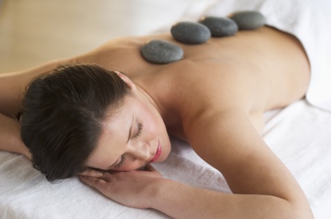 Woman receiving hot stone therapy.