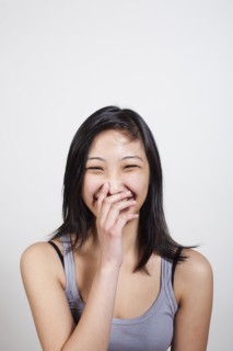 Young woman covering mouth when laughing. Photo : Winslow Productions
