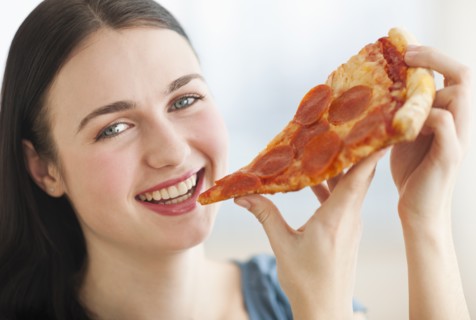 Portrait of smiling young woman eating pizza.