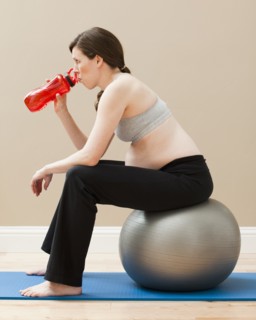 Young pregnant woman taking break from exercise. Photo : Mike Kemp