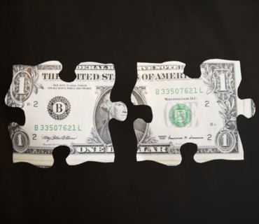 Studio shot of jigsaw pieces depicting one dollar bill. Photo : Jamie Grill Photography