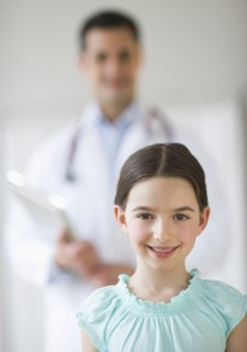 Portrait of girl (8-9), with doctor behind.