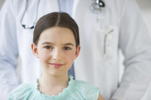 Portrait of girl (8-9), with doctor behind.