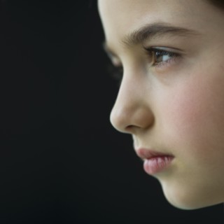 Studio profile of girl (8-9) on black background.