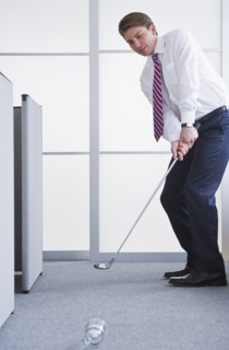 Businessman playing golf at office. Photo : Daniel Grill