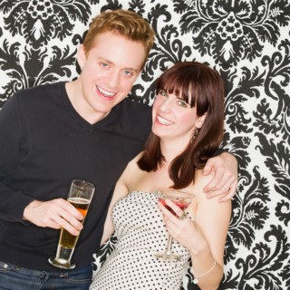 Studio portrait of young couple holding drinks. Photo : Daniel Grill