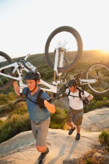 USA, California, Laguna Beach, Two men carrying bikes up hill.