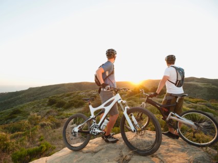 USA, California, Laguna Beach, Two bikers on hill looking at view.