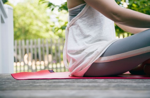USA, New York State, Long Island, woman sitting in yoga position in garden. Photo : Maisie Paterson