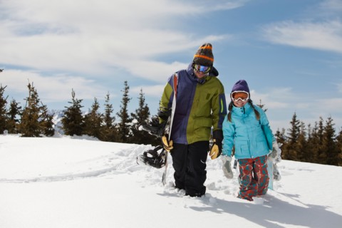 USA, Colorado, Telluride, Father and daughter (10-11) posing with snowboards in winter scenery.
